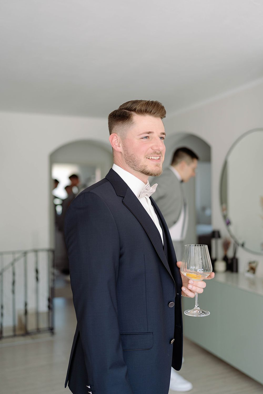 Person in formal attire holding a champagne glass in a bright interior space.