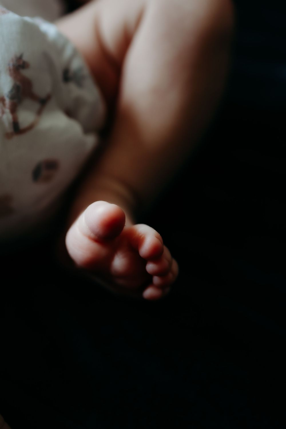 Close-up photo series of tiny baby feet and toes in soft focus against dark background.