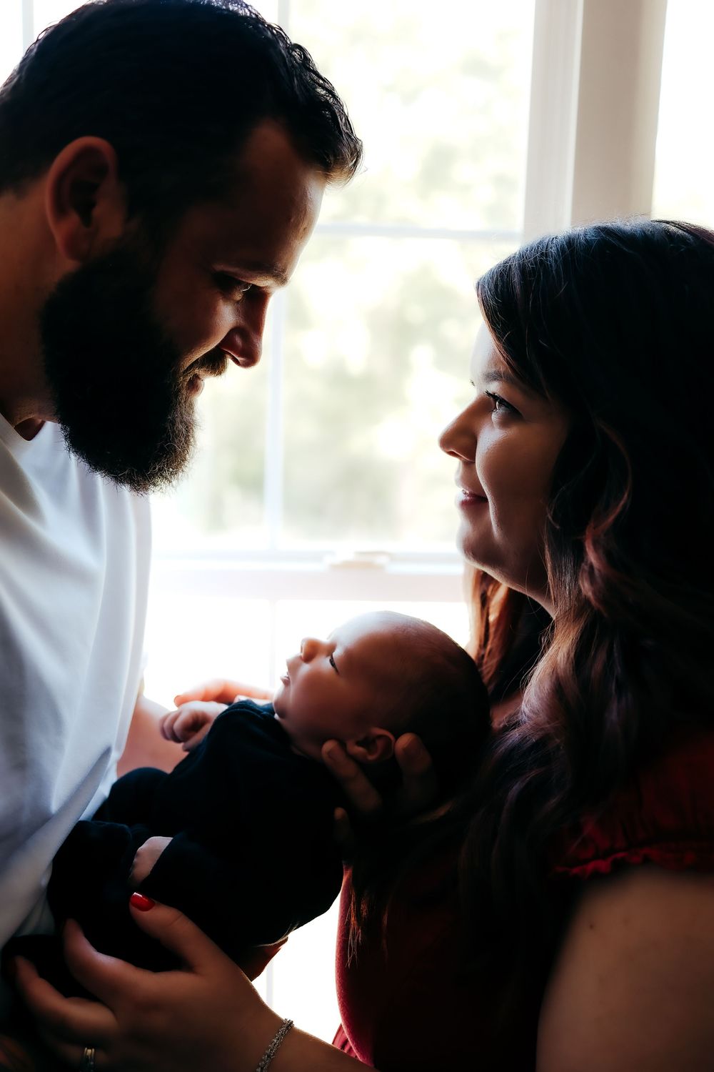 A series of intimate silhouetted photos showing tender family moments in natural window light.