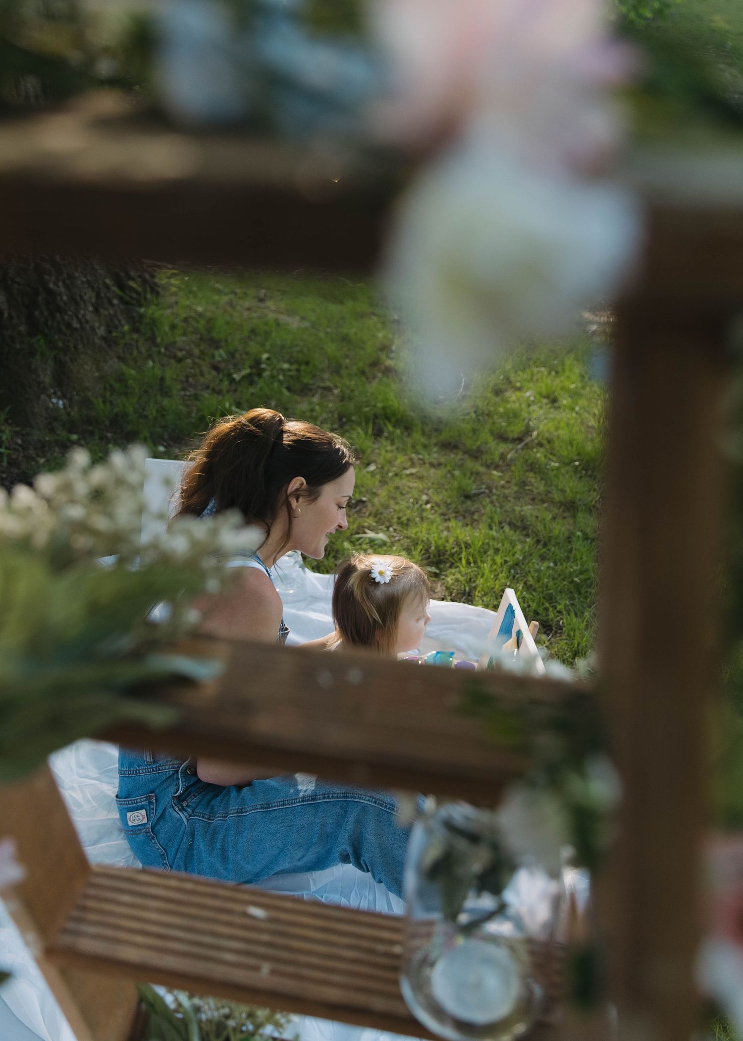 Candid family portrait in a spring meadow with children playing in the foreground on a sunny afternoon.