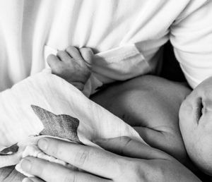 Intimate black and white image of newborn's hand grasping fabric.