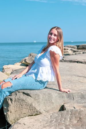 Summer portrait session on rocky coastal shoreline with blue ocean backdrop.