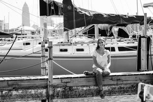 A line of sailboats and yachts docked at a marina under bright daylight.