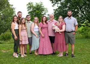 Group of people wearing coordinated pink and pastel outfits posing together on green grass.
