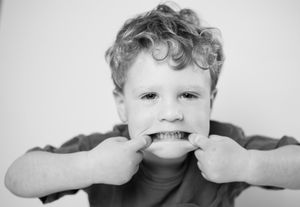 Black and white portrait of playfully pulling cheeks in expressive gesture.
