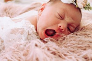 Close-up of newborn baby sleeping peacefully on soft pink blanket.