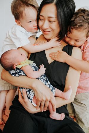 Intimate family moment with children embracing parent in black dress.
