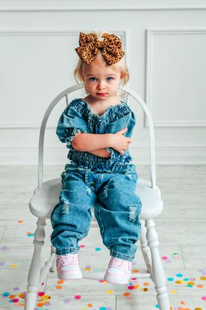 Series of photos showing child in denim outfit sitting on white chair surrounded by confetti.