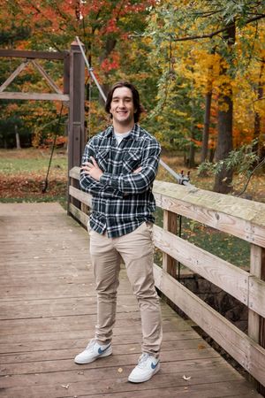 A casual autumn portrait on a wooden bridge surrounded by colorful fall foliage.