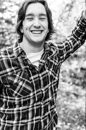 A black and white portrait featuring a plaid flannel shirt against a natural background.
