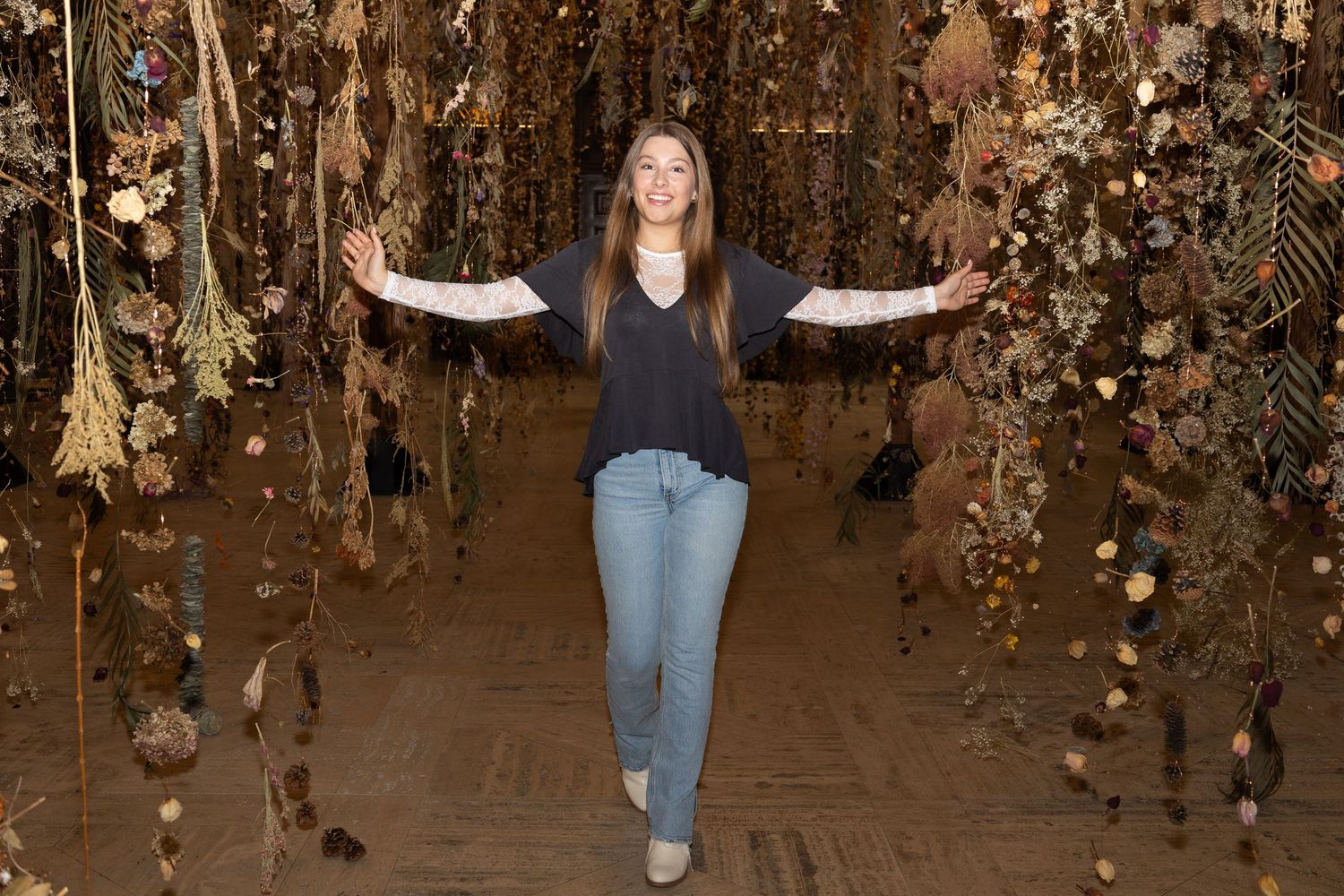 A joyful pose in a room decorated with hanging dried flowers and lights.