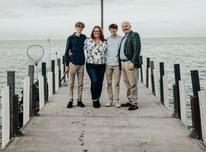 A family walking together on a wooden pier overlooking a misty waterfront.