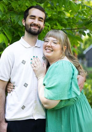 Couple in white and mint green outfits share joyful laughs during an outdoor photoshoot.