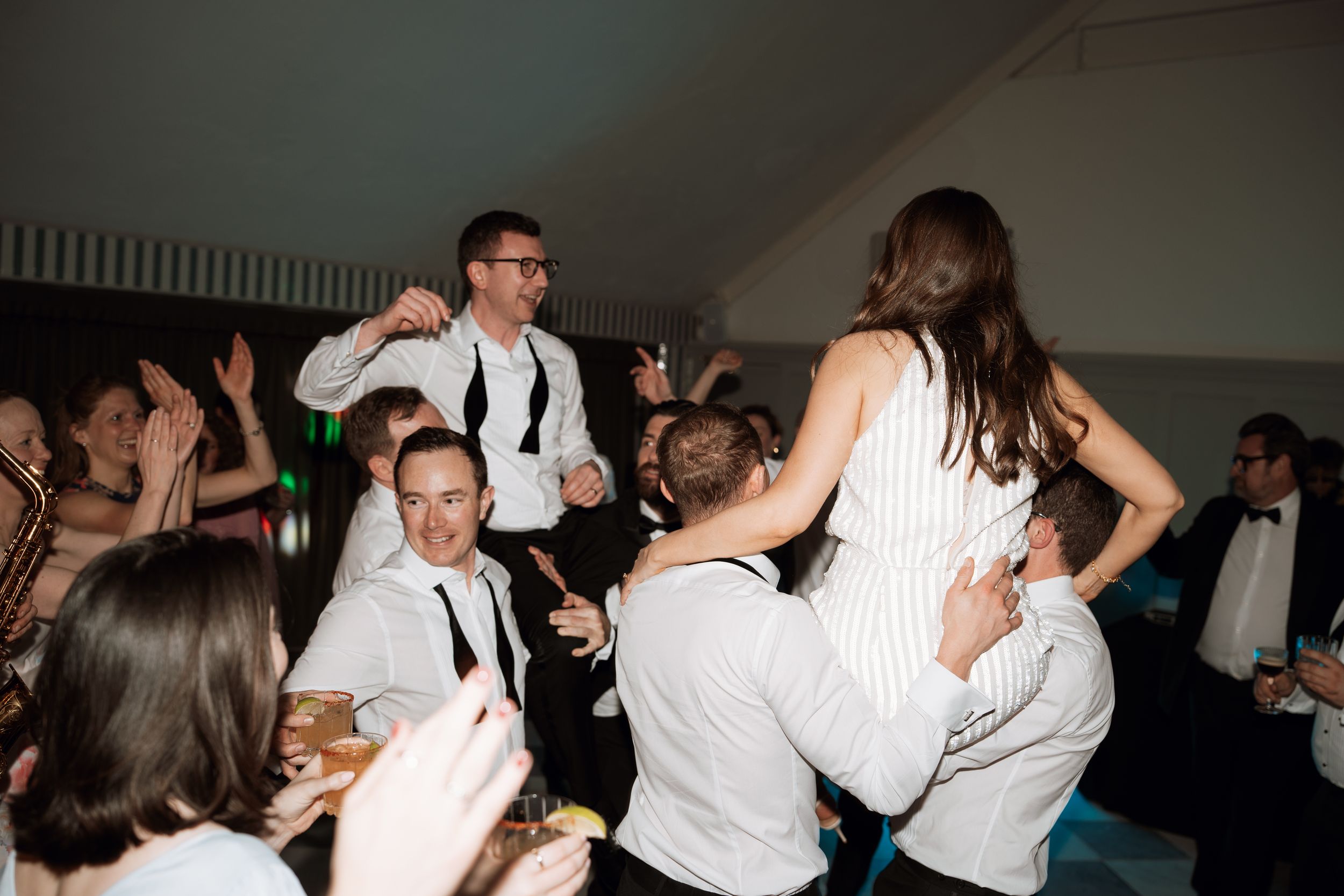 Crowd of people dancing energetically at a festive celebration with party guests in formal attire at kin house Wiltshire