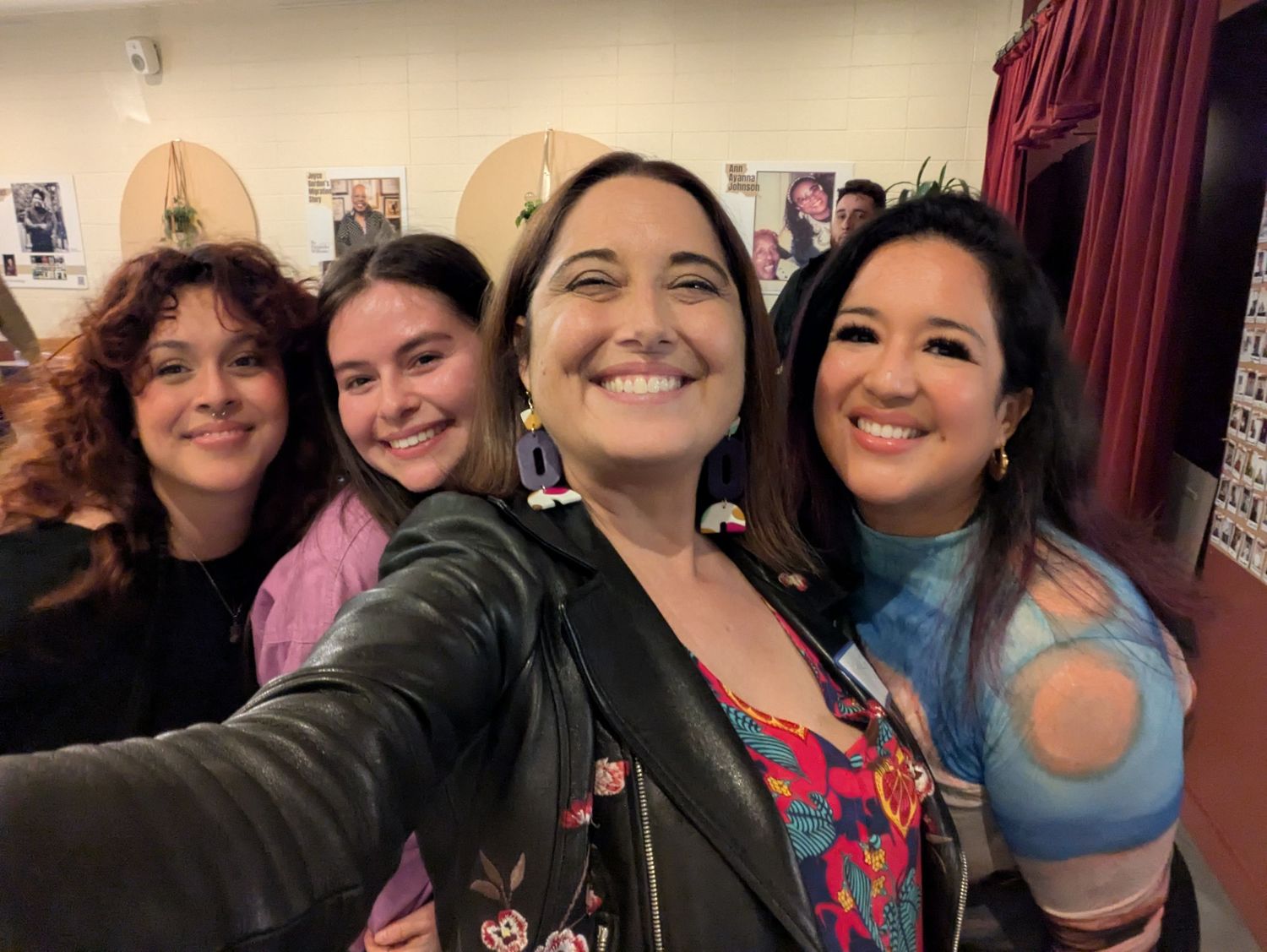 A group of four friends taking a smiling selfie together in casual attire.