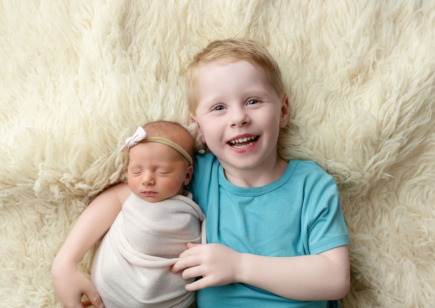Big brother smiling, holding newborn sister. Greenville SC newborn photographer, Easley SC newborn photographer