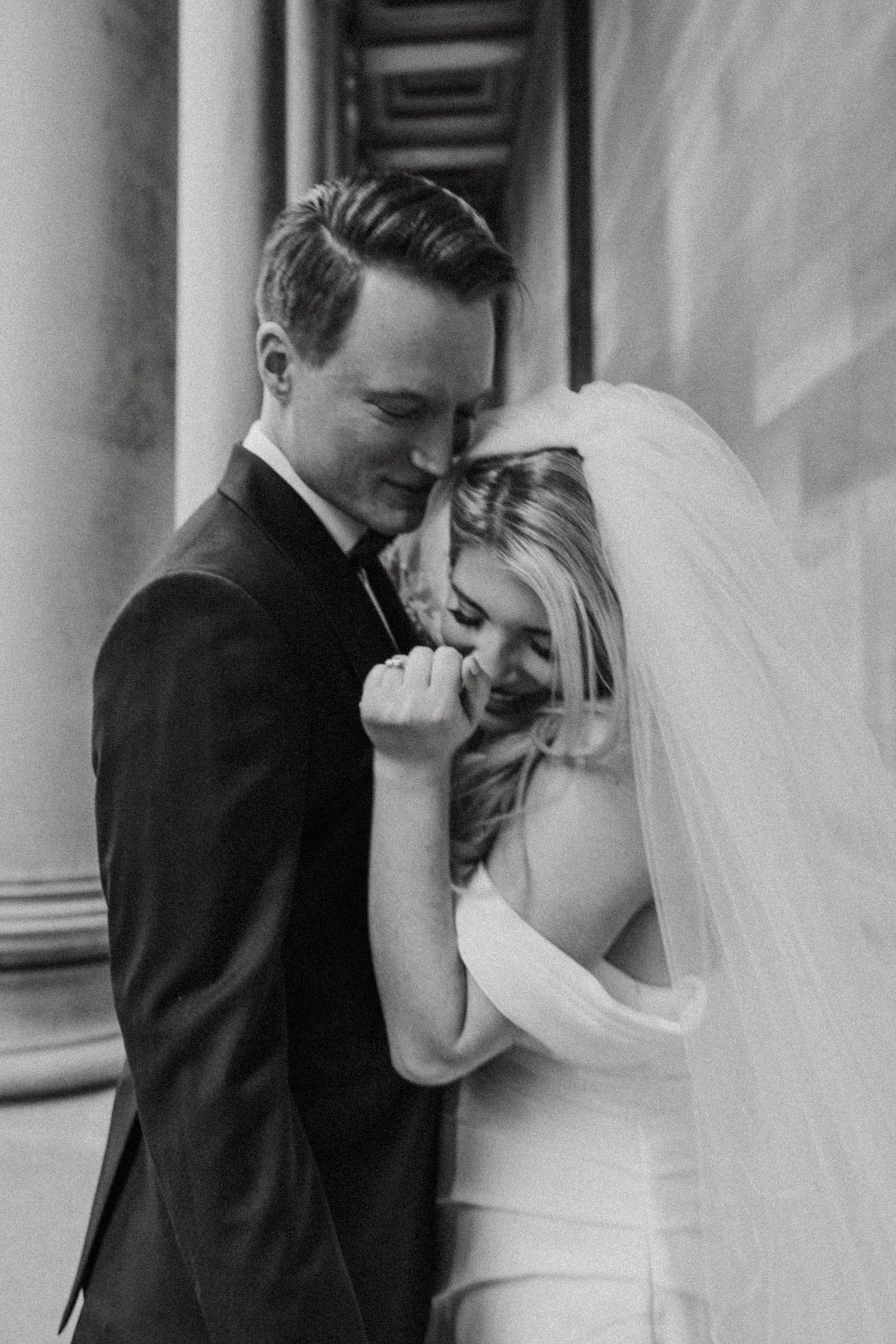 A candid black and white wedding photo capturing an intimate moment between newlyweds sharing a laugh together.
