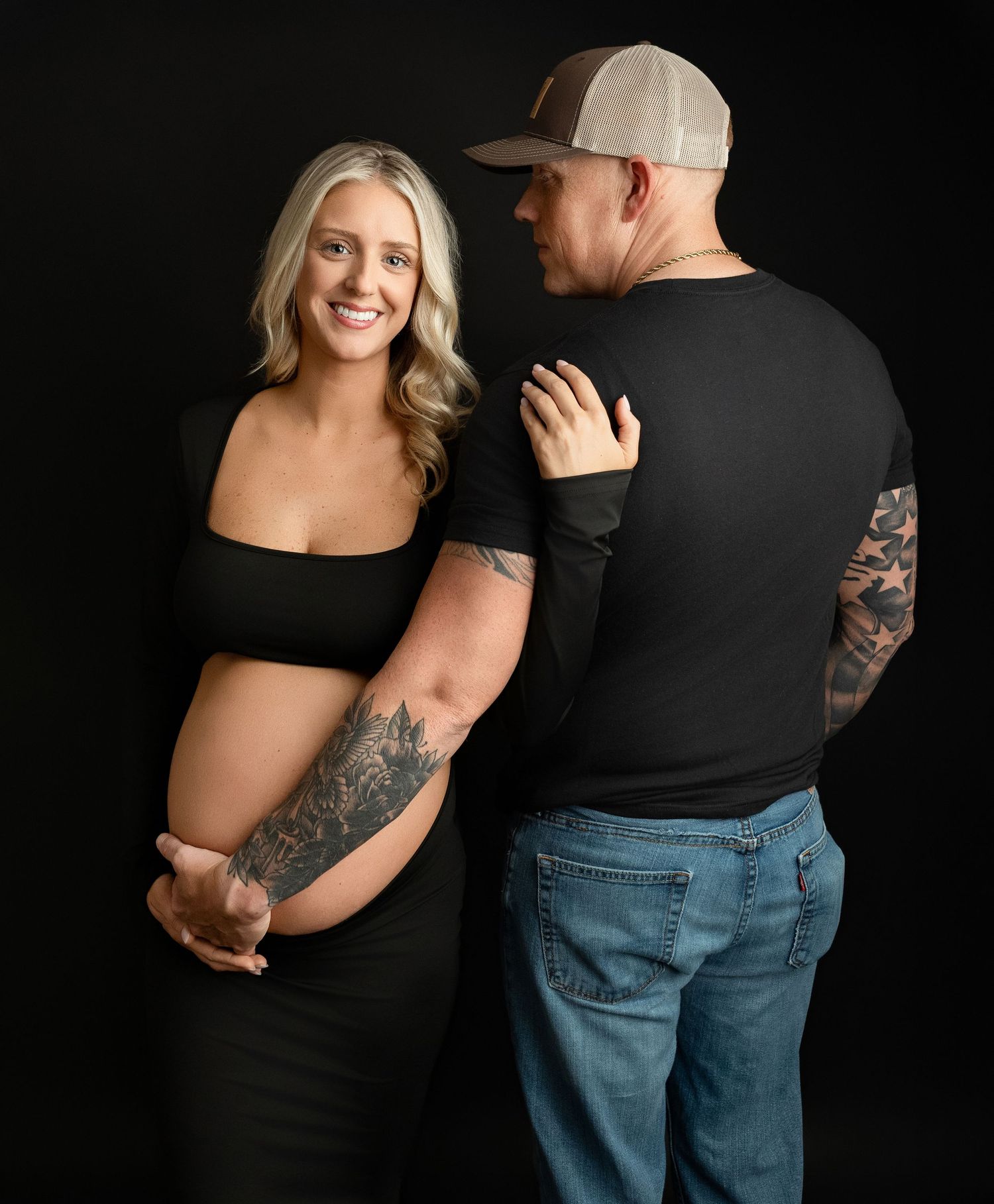 Mom is looking at the camera, smiling while Dad is holding her belly. for her maternity session. Greenville, SC newborn photographer,