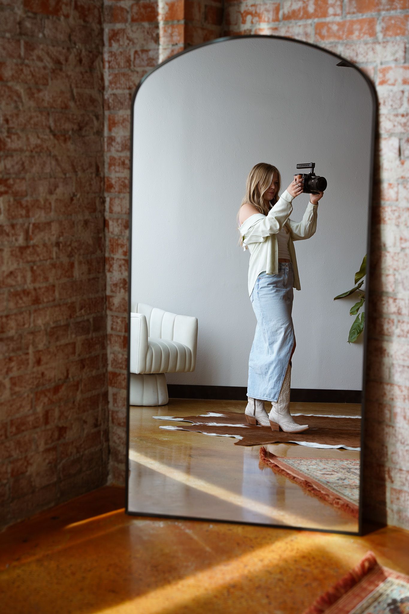 Photography equipment featuring a Sony camera, drone, charger and disco ball on white fur and wooden surface.