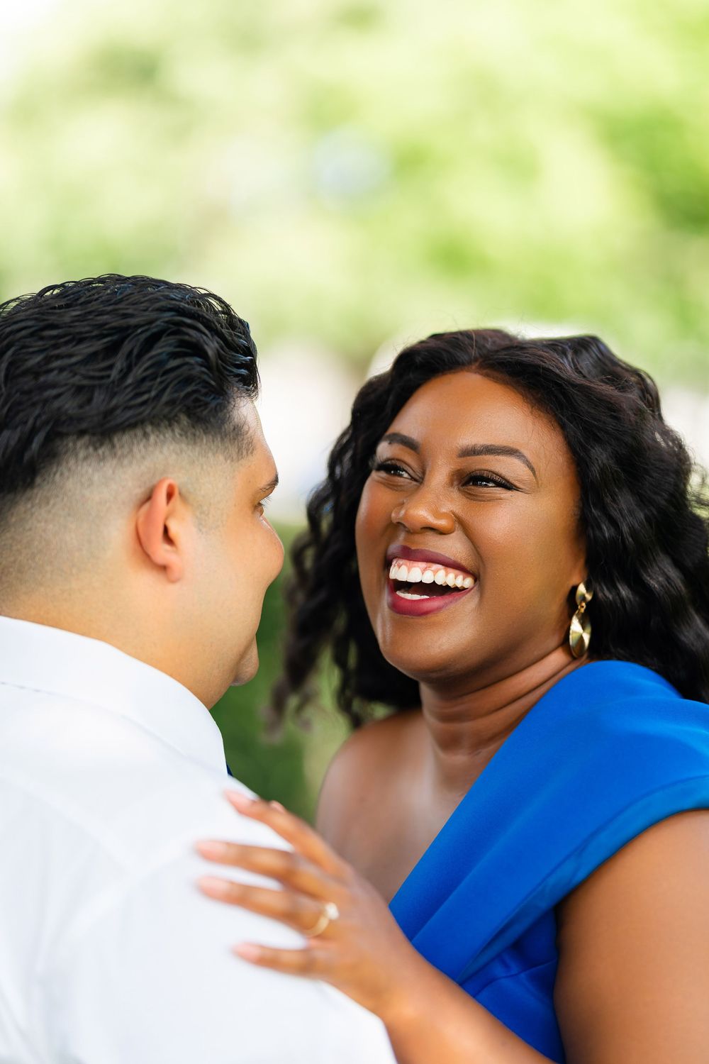 A couple sharing a joyful moment outdoors while wearing white and royal blue outfits.