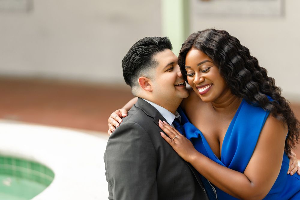A couple shares an intimate moment together as they embrace, with one person wearing a blue dress and the other in a suit.