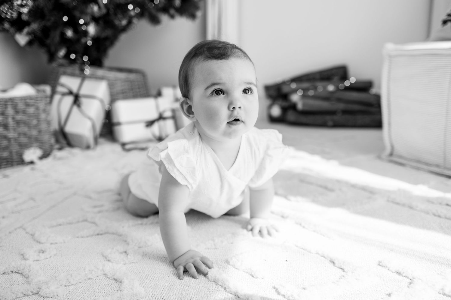 A collection of black and white photos showing a baby lying on a floor reaching and crawling.