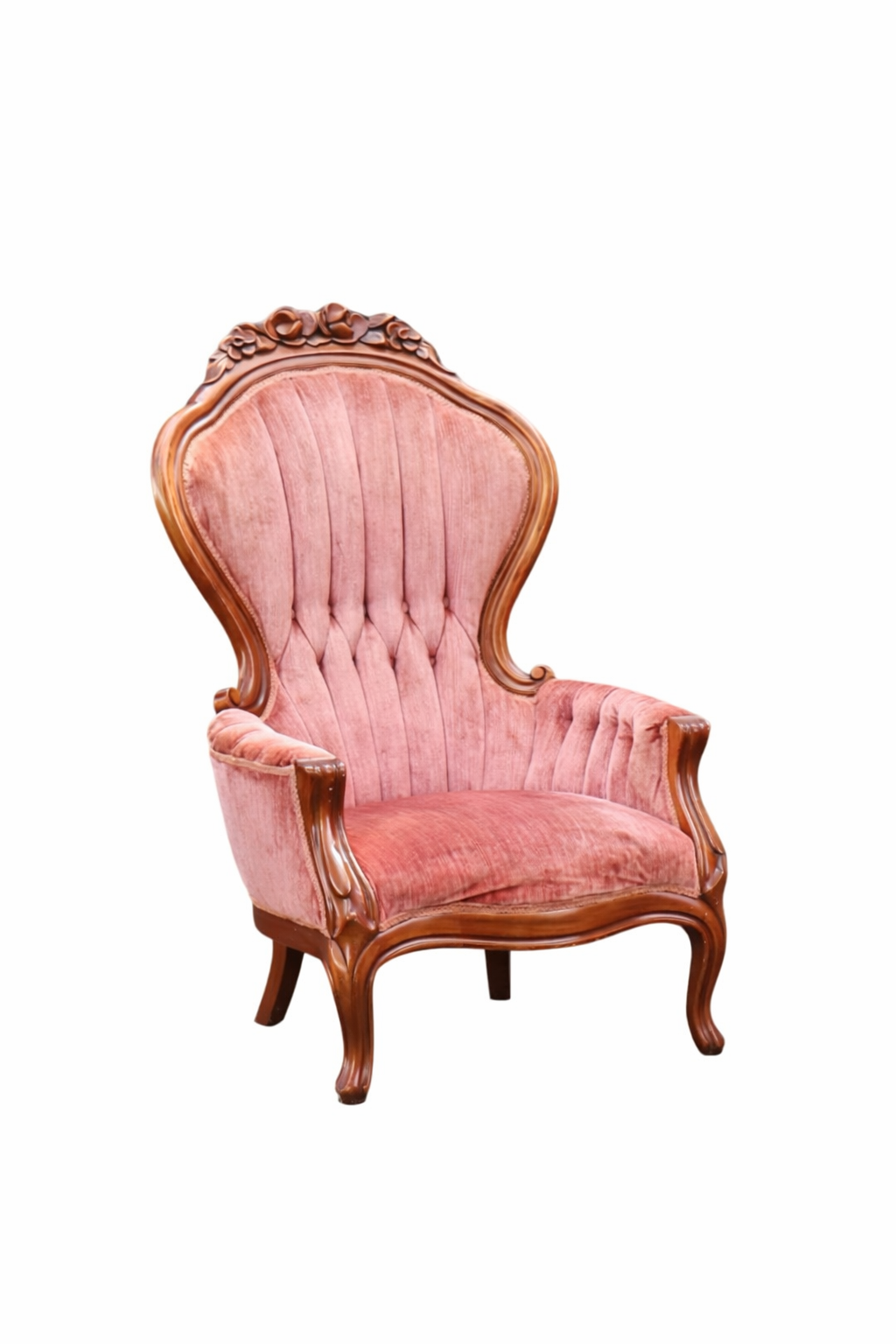A vintage Victorian-style armchair with pink velvet upholstery and wooden frame sits in a garden setting.