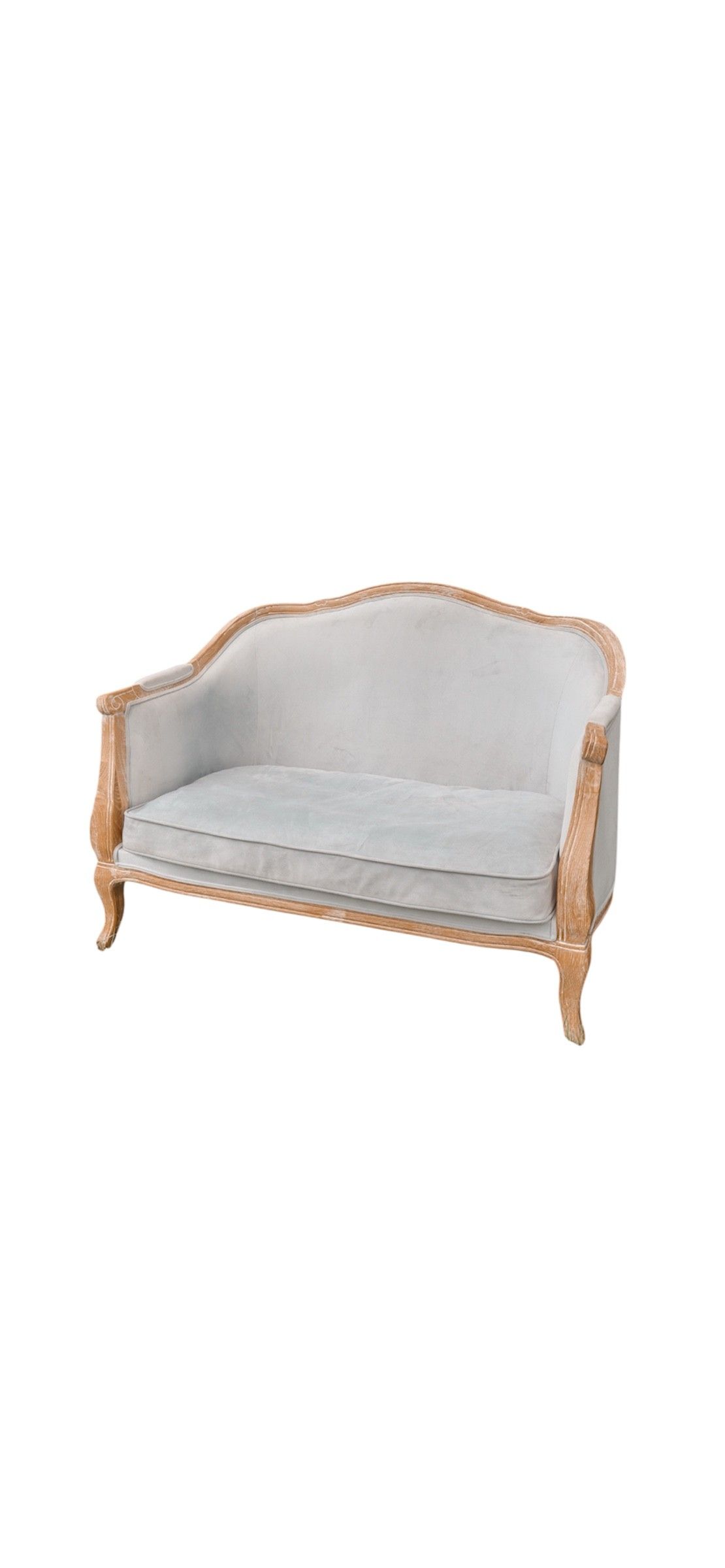 A vintage French-style settee with light gray upholstery and wooden frame sits elegantly on grass with trees in background.