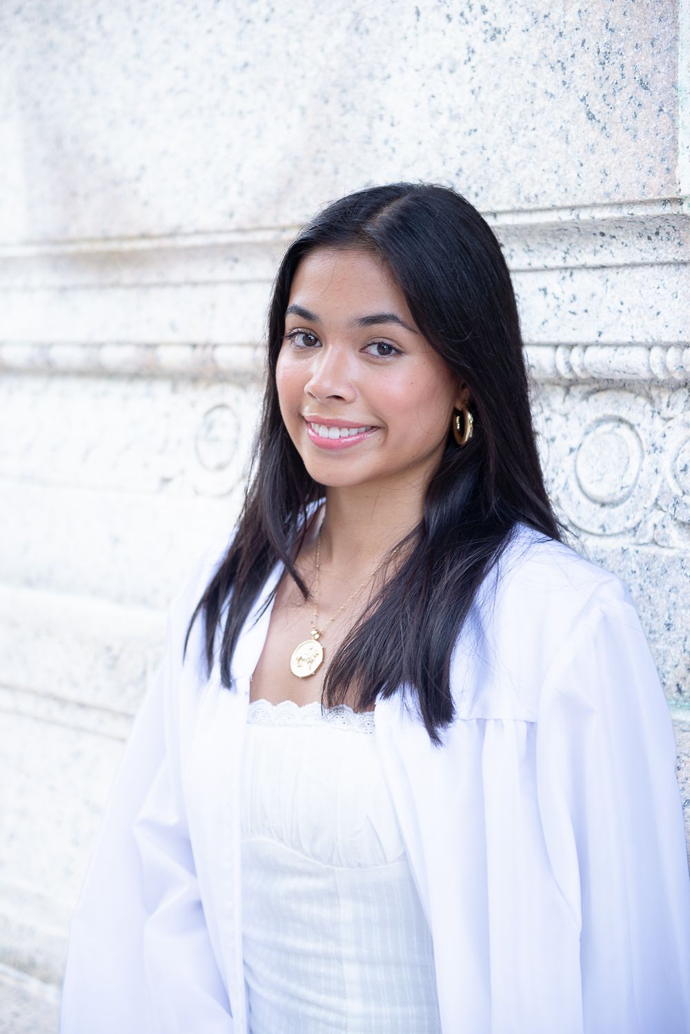Portrait against white stone architecture wearing classic white attire.