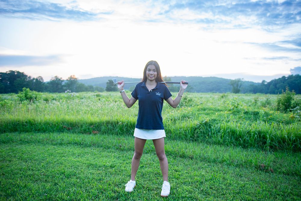 Seven sequential photos show someone jumping and twirling through a field of green grass under a blue summer sky.