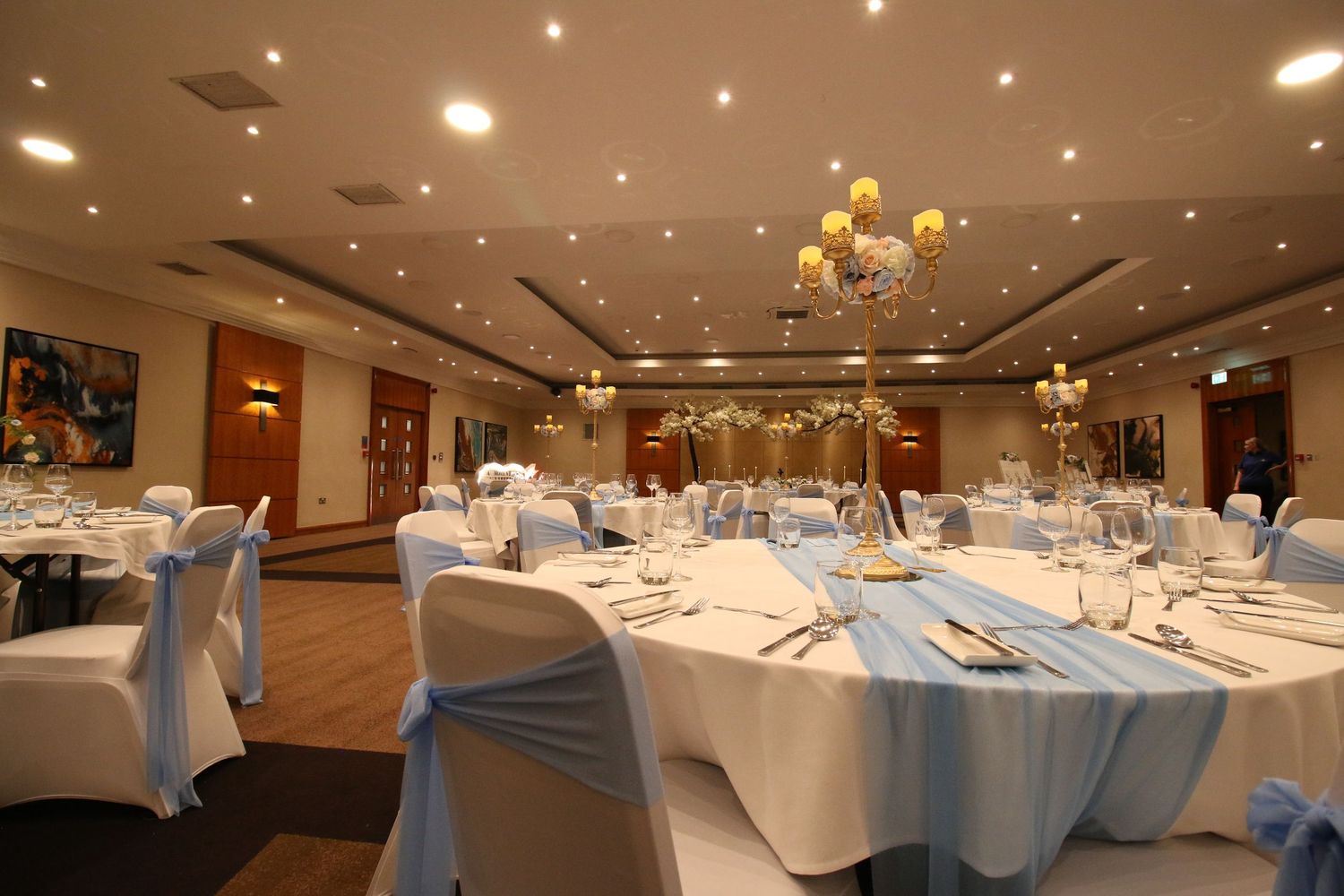 Elegant banquet hall setup with round tables and ceiling lighting.