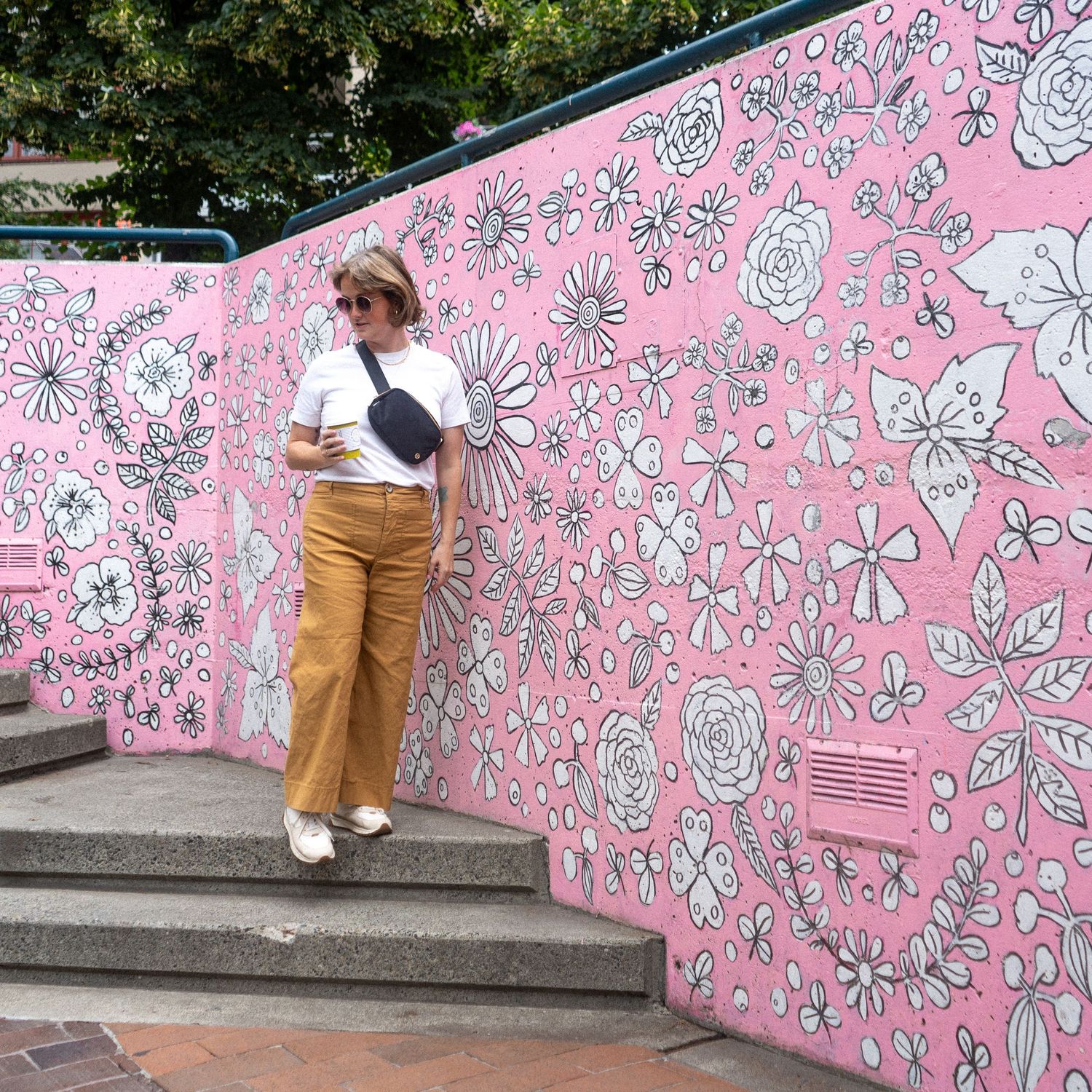 A pink wall with black and white floral pattern designs serving as a decorative mural.