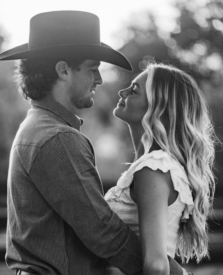 A romantic black and white western-style photo of a couple in an intimate close-up pose with backlit lighting.