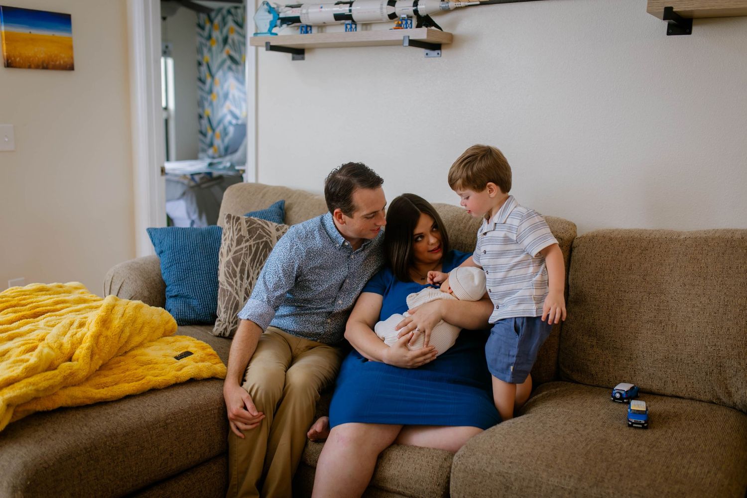 A tender sequence across multiple photos showing family affection on a gray couch by a sunny window.
