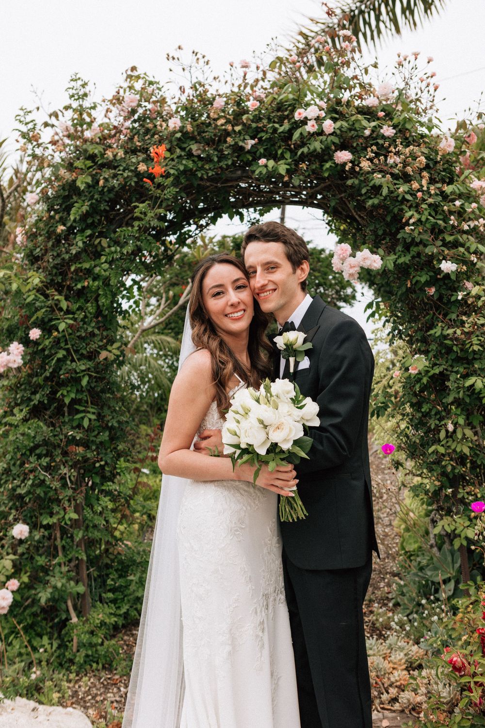 Bride and groom smile under a garden arch at a PCH wedding overlooking Malibu and the Pacific Ocean