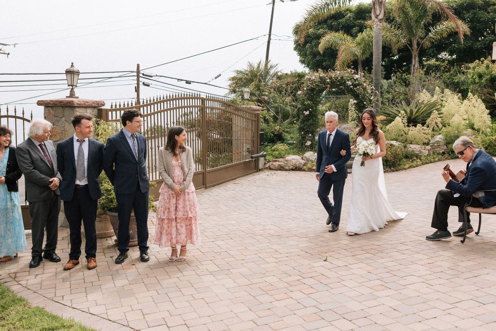 Bride and her father walking toward their family for a private Malibu wedding.