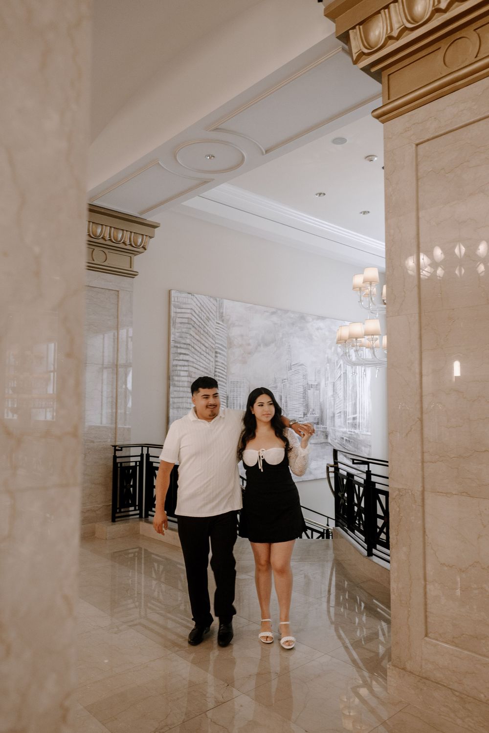 A couple walking in a bright hallway with marble floors and pillars shown in a cinematic style sequence.