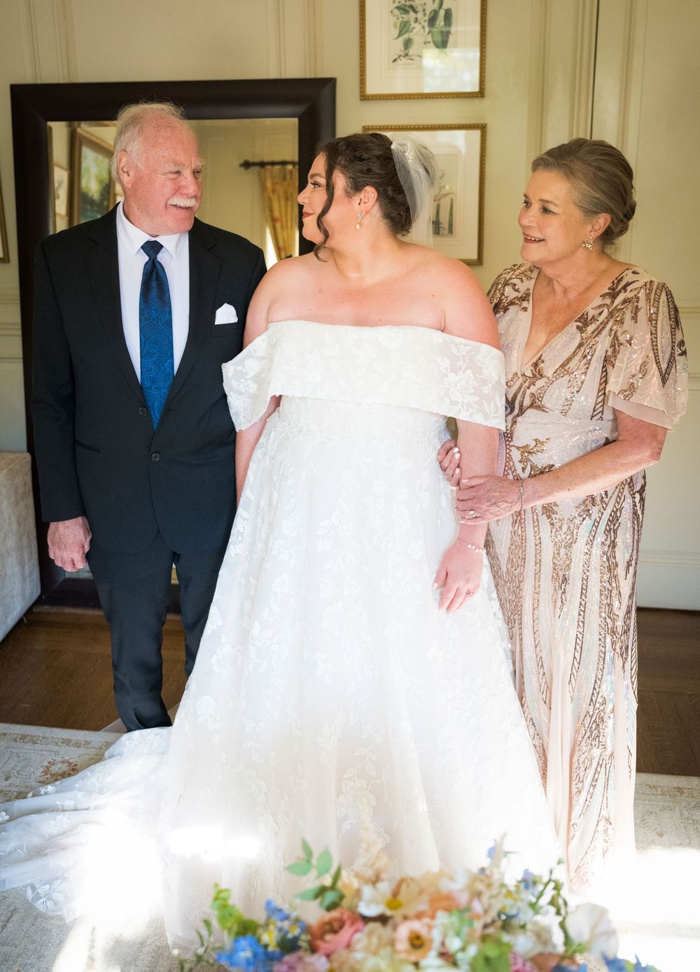 Wedding party gathered in an elegant room with the bride in white and others in formal attire.