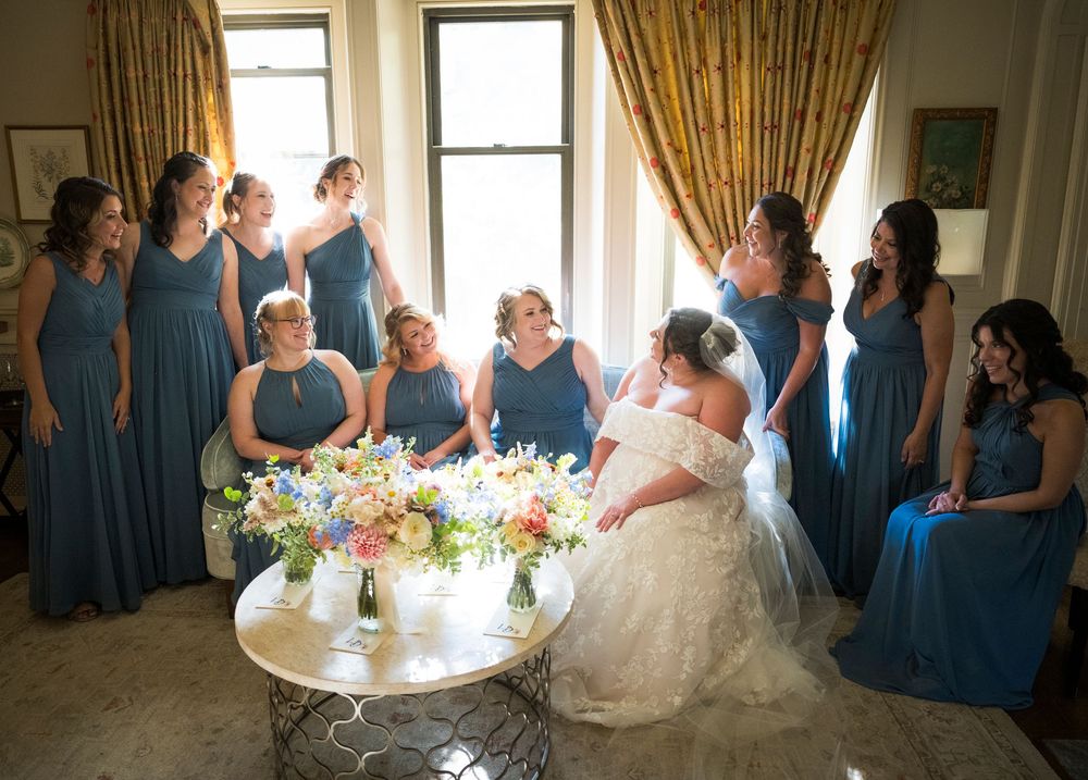 Wedding celebration scene with bridesmaids in blue dresses gathered around a decorated table.