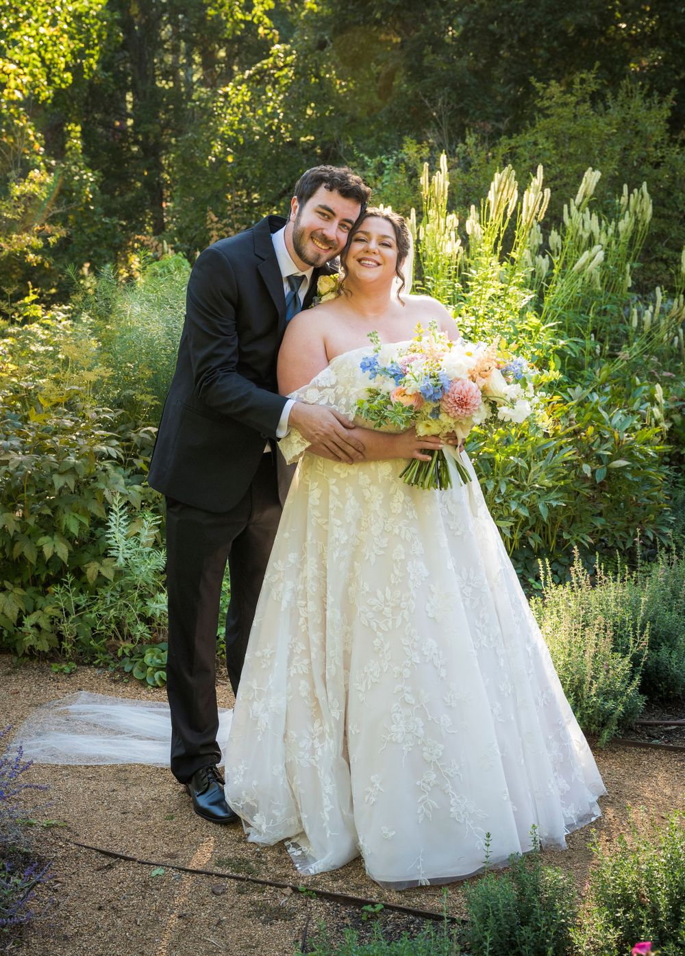 A romantic wedding photo session in a lush garden with a couple in formal attire and a flowing white gown.