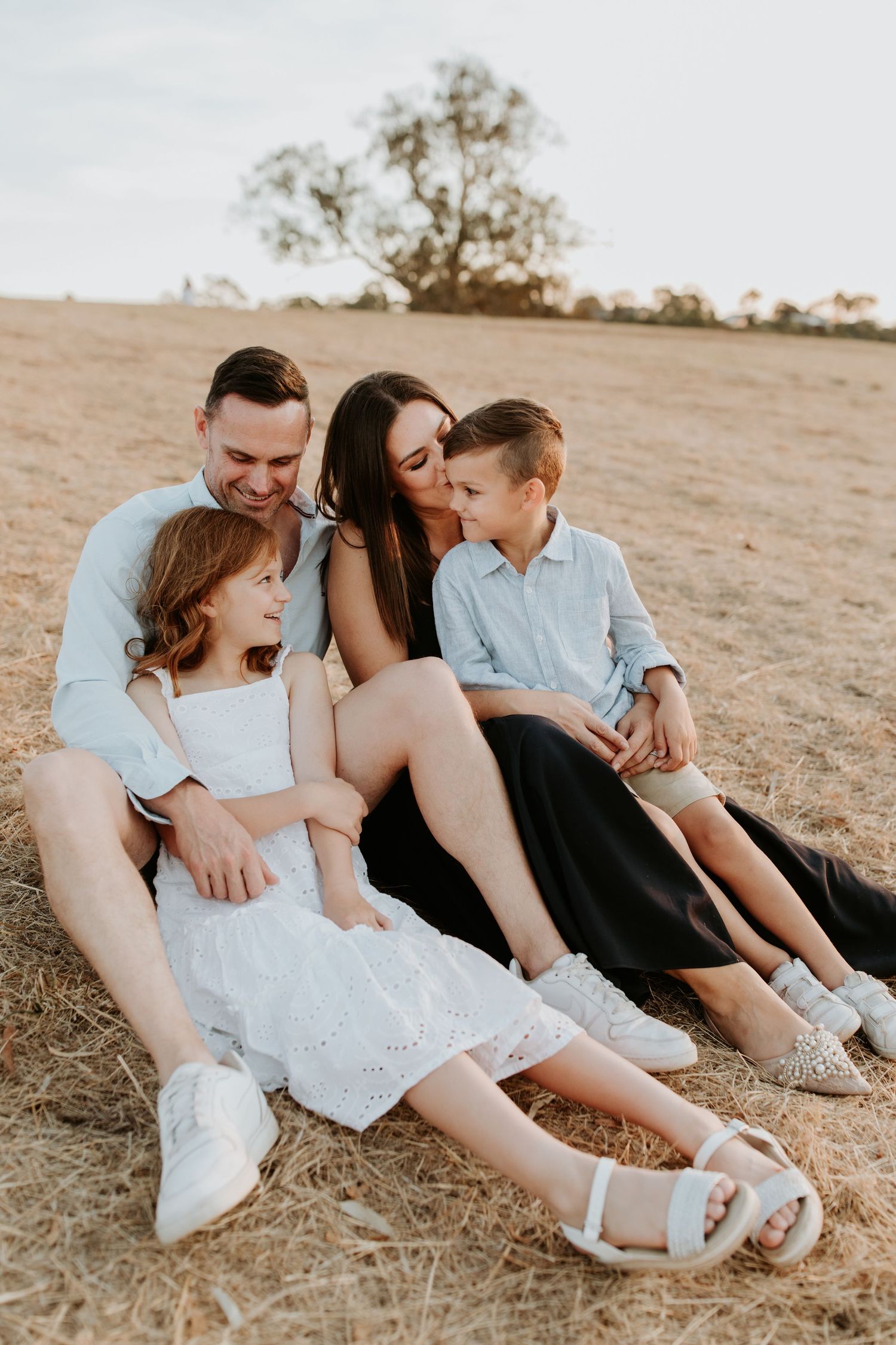 A family of four enjoying a fun moment together on a hillside in Adelaide at their family photoshoot with Lauren Lunn Photography.