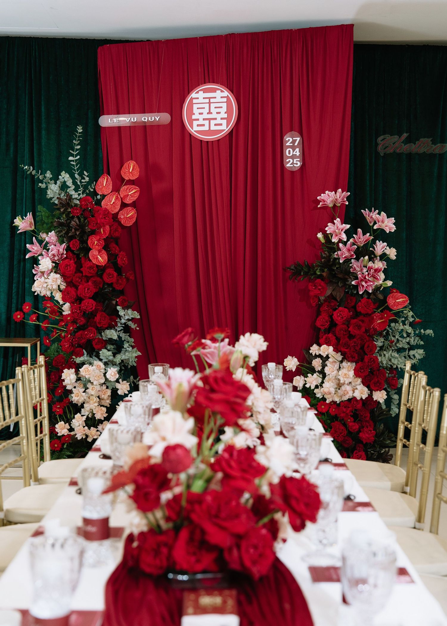 Elegant red and white wedding reception table setup with double happiness backdrop and floral centerpiece.