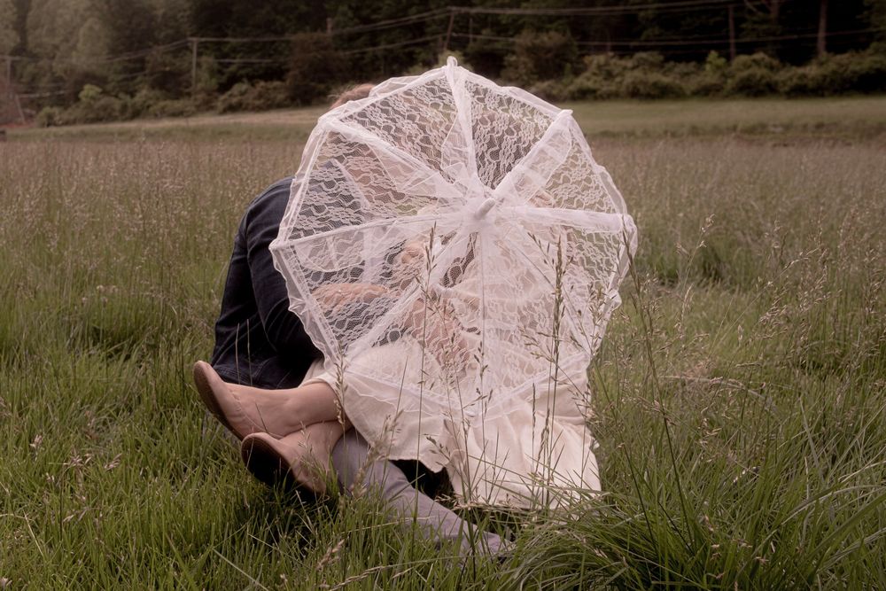 Romantic moment captured in a field with a vintage lace parasol.