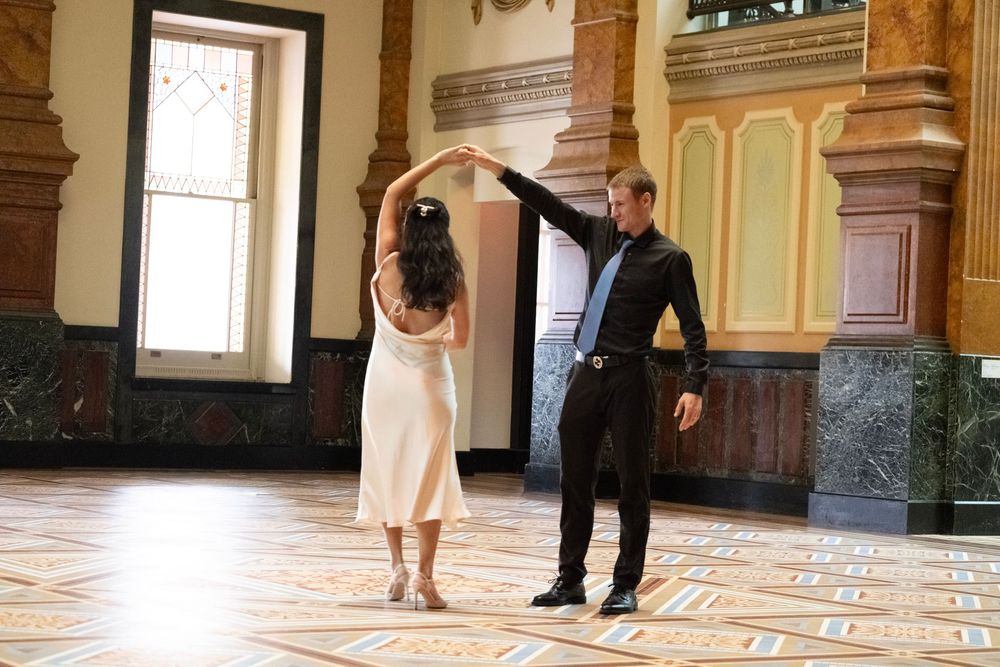 Couple dancing in a historic building with ornate mint green walls and marble floors.