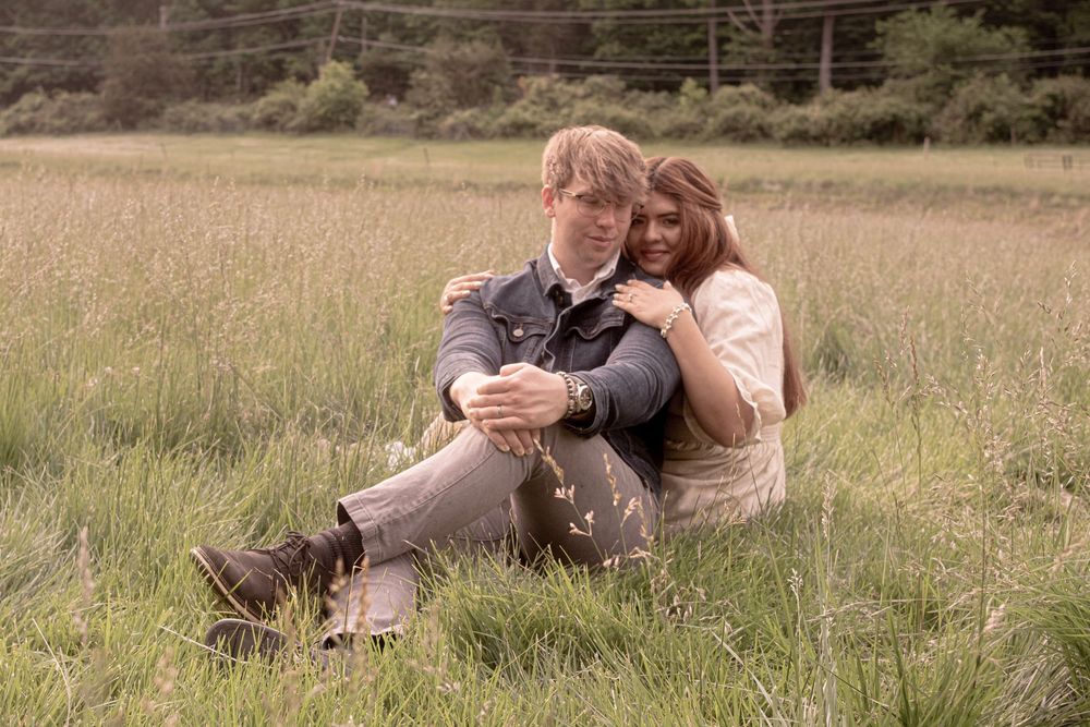 Couple relaxing together in a peaceful meadow during golden hour.