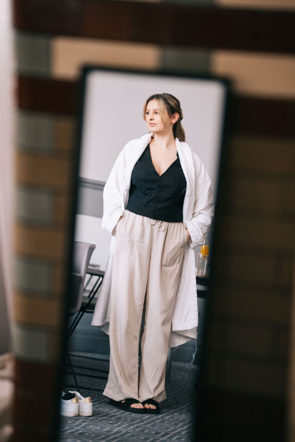 Person wearing casual white blazer and black top sits with relaxed professional styling.