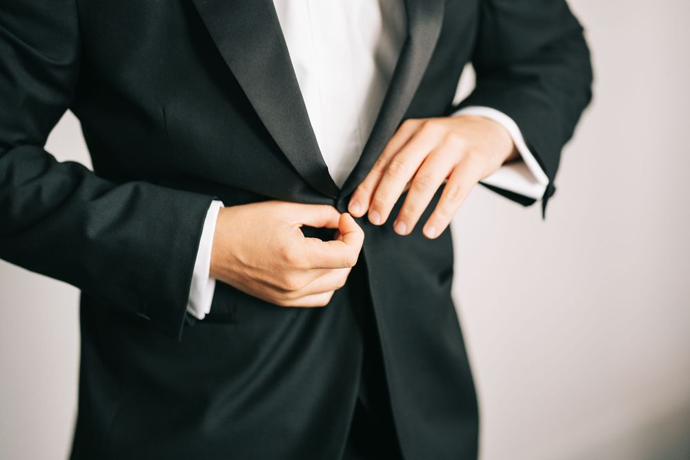 Professional outfit details showing black blazer with white shirt and elegant accessories.
