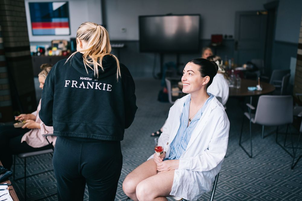 Two people seated in a room while getting ready, one wearing a black Frankie sweatshirt and another in a white robe.