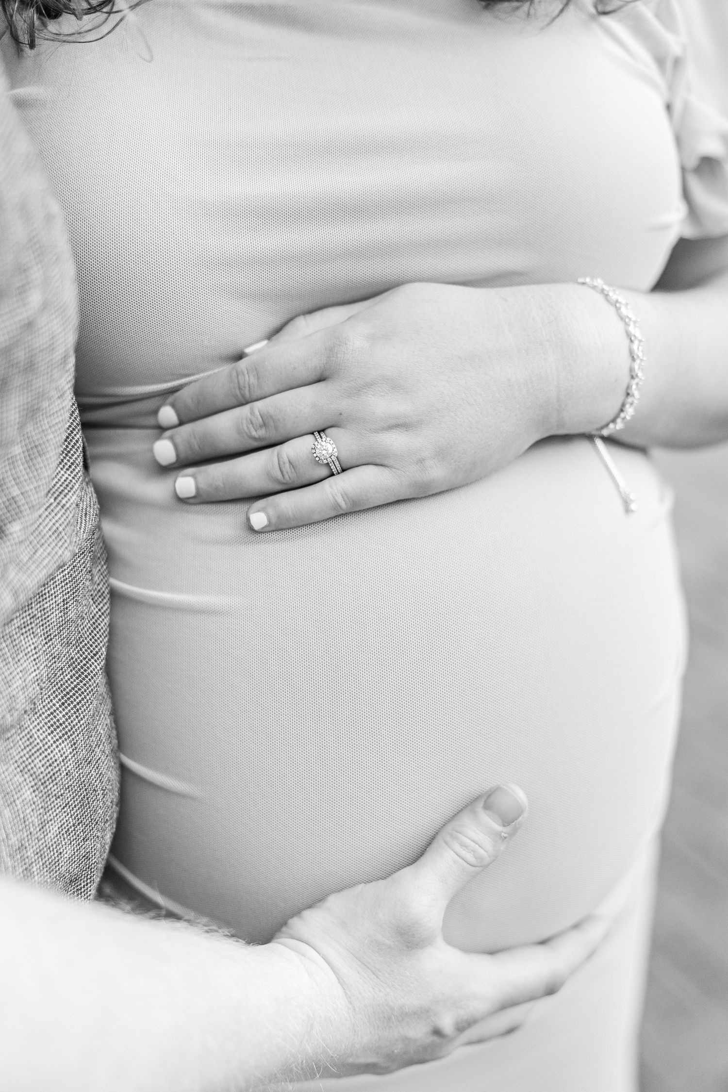 Close-up black and white photos of hands cradling pregnant belly with engagement ring visible.