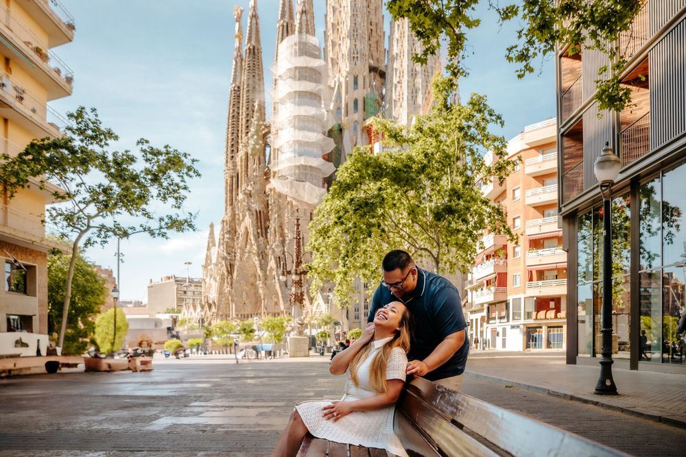 Seham leaning into Cyrill as soft morning light filters through Sagrada Familia